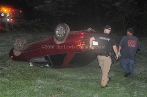 Deputy Eric Poynter and Hammer Cooper, with Garrison Fire and Rescue, examine the scene of a single vehicle accident Thursday evening on Montgomery Road. The driver reportedly left the scene before officials arrived. - Photo by Dennis Brown