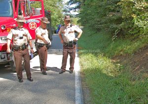 Deputy John Byard, Sheriff Johnny Bivens, and Lt. Bryon Walker examine the scene of a fatal single-vehicle crash on Montgomery Road south of Garrison. - Dennis Brown Photo